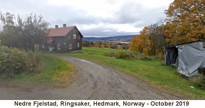 Nedre Fjelstad, Ringsaker, Hedmark, Norway: Color photo, taken in October 2019, of a dirt driveway leading past a tarp-covered shed to a brown two-story farmhouse on a hillside that overlooks a broad valley leading down to a distant lake; the trees bear yellow and orange autumn leaves